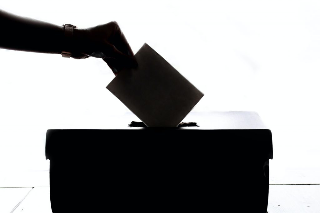 Hand placing vote into a ballot box